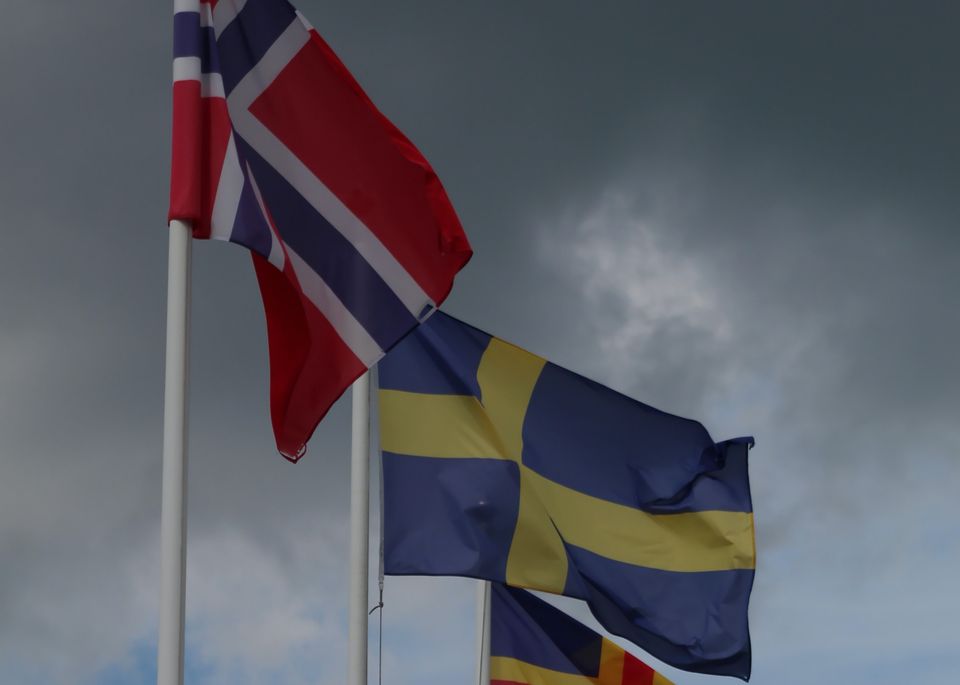 Swedish and Norwegian flags over a cloudy sky